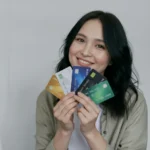 Happy woman smiling and holding five credit cards, representing high cashback credit card options and smart financial choices in 2025.